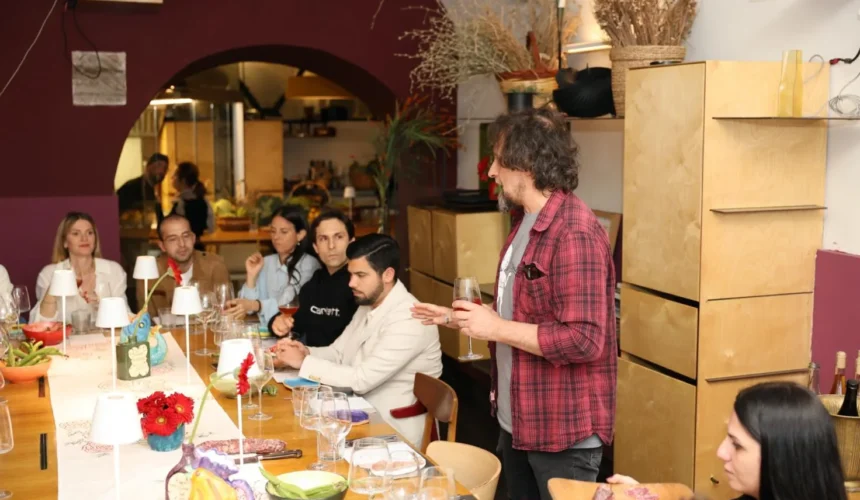 Persone sedute a tavola durante una cena degustazione con vino e specialità gastronomiche in un ristorante moderno.