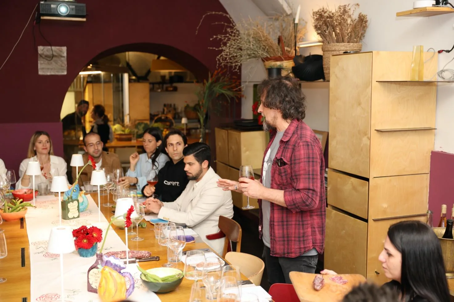 Persone sedute a tavola durante una cena degustazione con vino e specialità gastronomiche in un ristorante moderno.