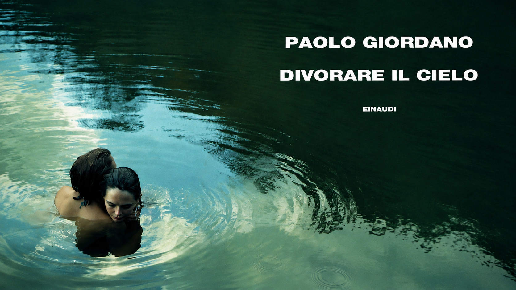 Due persone abbracciate immerse nell’acqua scura e riflettente, con il titolo “Divorare il cielo” di Paolo Giordano in bianco nella parte superiore destra dell’immagine.