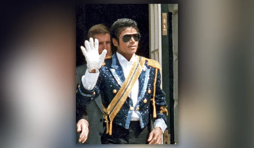 Michael Jackson indossa un abito decorato e saluta con il celebre guanto bianco durante un’apparizione pubblica.