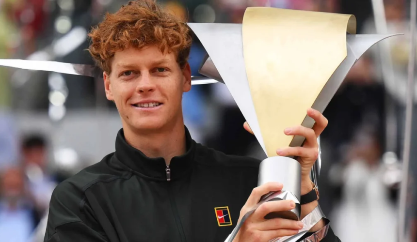 Il tennista Jannik Sinner tiene in mano il trofeo del torneo di Madrid mentre sorride davanti ai fotografi.