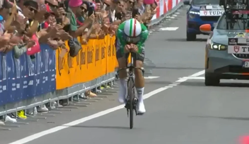 Il ciclista italiano Filippo Ganna pedala in posizione aerodinamica durante una cronometro con il pubblico ai lati della strada.