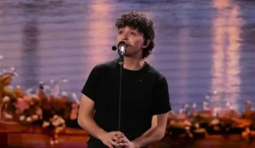 Il cantante Lorenzo Salvetti canta al microfono durante un’esibizione dal vivo su un palco illuminato.