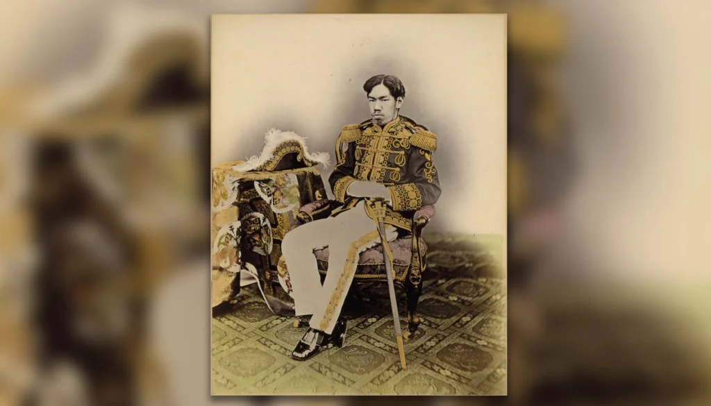 Ritratto storico dell’Imperatore Meiji seduto in uniforme militare decorata con una sciabola accanto a sé.