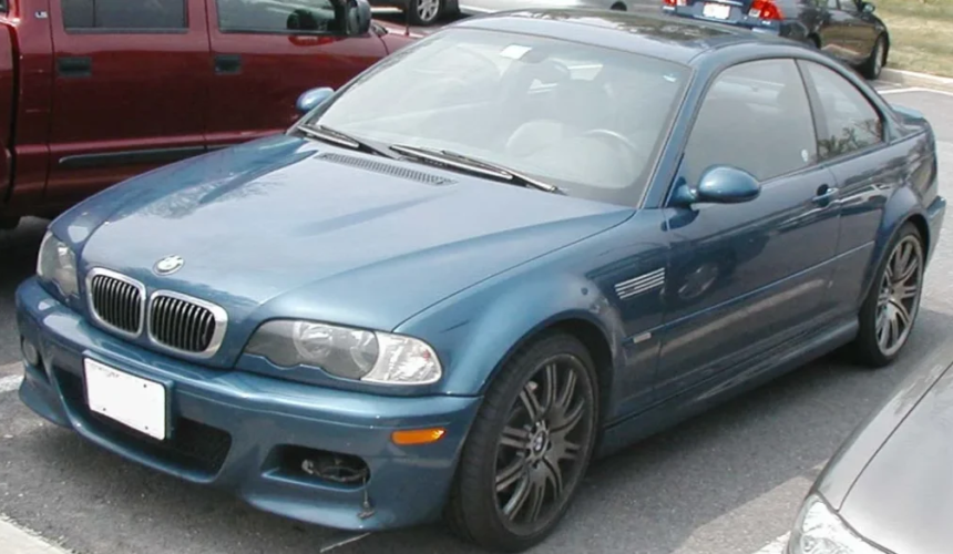 BMW M3 Coupé blu parcheggiata in un’area urbana con design sportivo e cerchi in lega scuri.