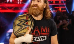 Sami Zayn tiene sulla spalla una cintura di campione WWE durante un evento di wrestling.
