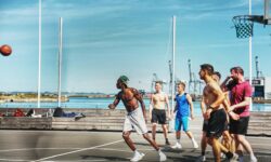 Persone che giocano a basket all’aperto vicino al mare.