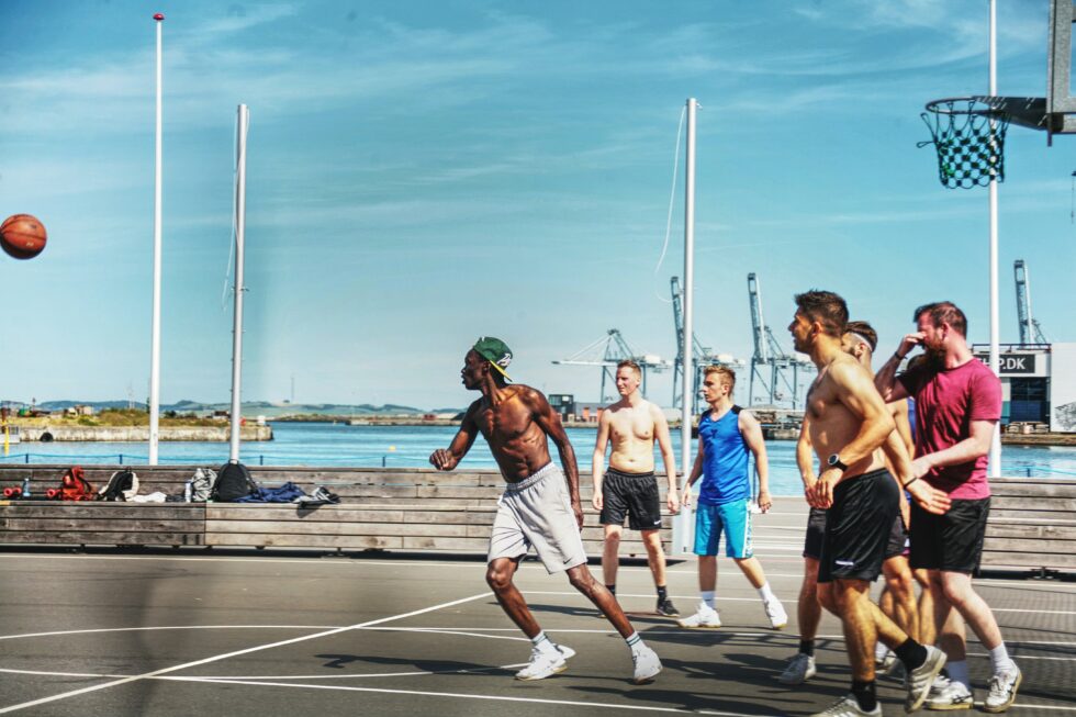 Persone che giocano a basket all’aperto vicino al mare.
