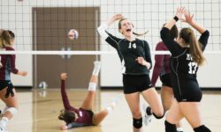 Giocatrici di pallavolo che festeggiano un punto durante una partita indoor.